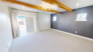 Empty room with light carpet and beam ceiling