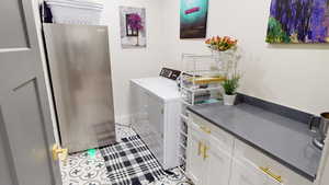 Laundry with cabinets, light tile patterned floors, and independent washer and dryer