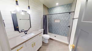 Bathroom featuring walk in shower, tile patterned floors, vanity, and toilet