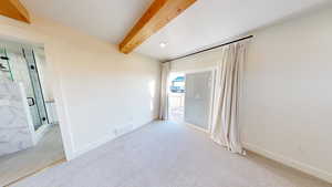 Spare room featuring light colored carpet and beam ceiling