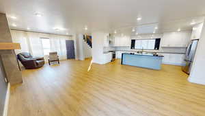 Kitchen featuring white cabinetry, appliances with stainless steel finishes, backsplash, and light wood-type flooring