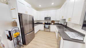 Kitchen featuring white cabinetry, appliances with stainless steel finishes, light hardwood / wood-style floors, and sink