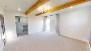 Carpeted spare room with beam ceiling