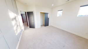 Unfurnished bedroom featuring light carpet and a closet