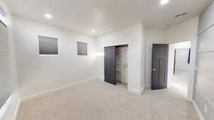 Unfurnished bedroom with light carpet and a closet