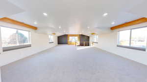 Interior space with light carpet and vaulted ceiling with beams