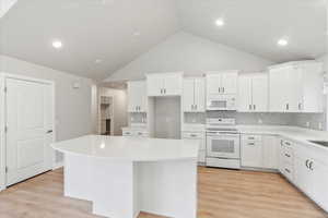 Kitchen featuring white cabinetry, white appliances, and a center island