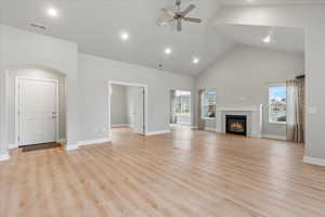 Unfurnished living room featuring high vaulted ceiling, a healthy amount of sunlight, light hardwood / wood-style floors, and a tile fireplace