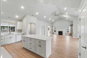 Kitchen featuring sink, white dishwasher, a kitchen island, ceiling fan, and white cabinets