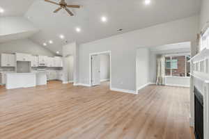 Unfurnished living room featuring high vaulted ceiling, ceiling fan, and light wood-type flooring