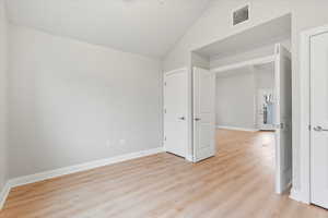 Unfurnished bedroom with vaulted ceiling and light hardwood / wood-style floors