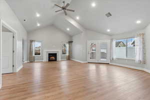 Unfurnished living room featuring ceiling fan, high vaulted ceiling, a fireplace, and light hardwood / wood-style floors