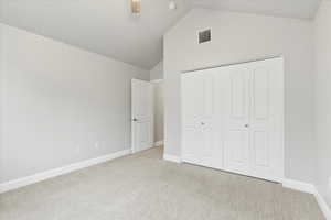 Unfurnished bedroom featuring ceiling fan, light colored carpet, high vaulted ceiling, and a closet