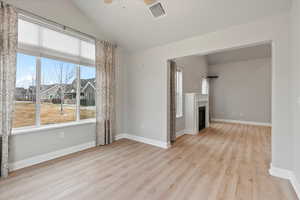 Unfurnished living room with vaulted ceiling, ceiling fan, and light hardwood / wood-style floors