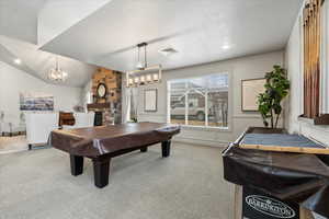 Playroom with lofted ceiling, a stone fireplace, pool table, and carpet flooring