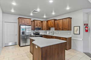 Kitchen featuring appliances with stainless steel finishes, a center island, sink, and light tile patterned floors