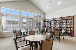 Dining space featuring carpet, plenty of natural light, and high vaulted ceiling