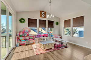 Playroom featuring an inviting chandelier, vaulted ceiling, and hardwood / wood-style flooring