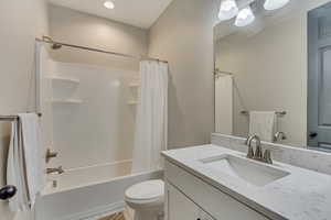 Full bathroom with toilet, vanity, shower / bathtub combination with curtain, and tile patterned flooring