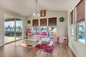 Playroom with lofted ceiling, hardwood / wood-style flooring, a wealth of natural light, and a chandelier