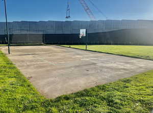 View of tennis court with a yard, fence, and community basketball court