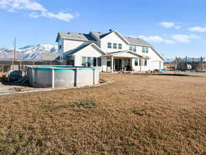 Back of house featuring a trampoline, a mountain view, and a lawn