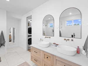 Bathroom with tile patterned flooring, a shower, stacked washer / drying machine, and vanity