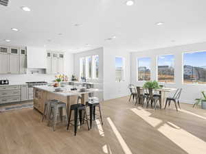 Kitchen with premium range hood, a breakfast bar area, white cabinetry, a kitchen island, and light hardwood / wood-style floors