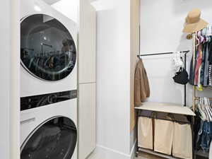 Primary suite walk-in closet featuring stacked washer and dryer