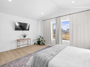 Primary bedroom featuring wood-type flooring and lofted ceiling