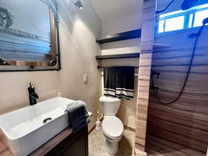 Bathroom with vanity, tile patterned floors, toilet, and a shower