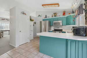 Kitchen with lofted ceiling, appliances with stainless steel finishes, kitchen peninsula, and light colored carpet