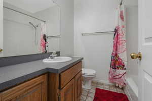 Full bathroom featuring vanity, tile patterned flooring, shower / bath combo, and toilet