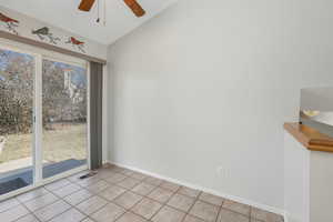 Tiled empty room with ceiling fan and vaulted ceiling