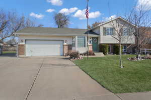 Tri-level home featuring a garage and a front lawn