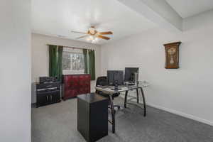 Carpeted office space featuring beam ceiling and ceiling fan