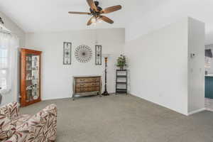 Sitting room with ceiling fan, light colored carpet, and vaulted ceiling