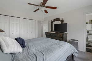 Carpeted bedroom with two closets and ceiling fan