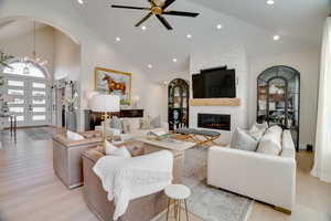 Living room with an inviting chandelier, a fireplace, high vaulted ceiling, and light hardwood / wood-style flooring