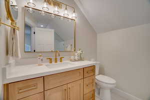 Bathroom featuring lofted ceiling, toilet, tile patterned flooring, and vanity