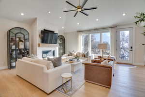 Living room with light hardwood / wood-style flooring, a fireplace, and high vaulted ceiling