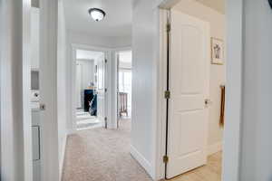 Corridor with light carpet and a textured ceiling