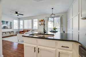 Kitchen featuring white cabinetry, dark hardwood / wood-style flooring, ceiling fan with notable chandelier, and sink