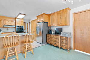 Kitchen featuring a kitchen breakfast bar, stainless steel fridge, oven, and kitchen peninsula