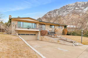 View of front of property featuring a mountain view, a garage, and a front yard