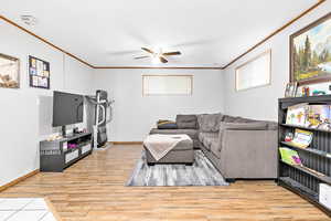 Living room with ceiling fan, ornamental molding, and light hardwood / wood-style flooring