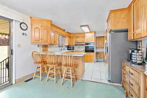 Kitchen featuring black appliances, sink, a kitchen bar, and kitchen peninsula