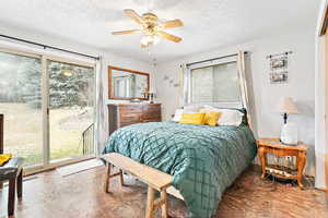 Bedroom featuring a textured ceiling, multiple windows, and access to outside