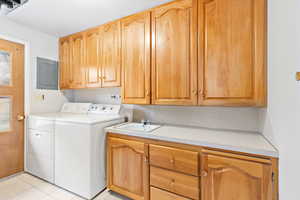 Laundry room featuring sink, cabinets, separate washer and dryer, light tile patterned floors, and plenty of natural light