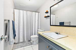 Bathroom featuring tile patterned floors, toilet, a shower with curtain, a textured ceiling, and vanity